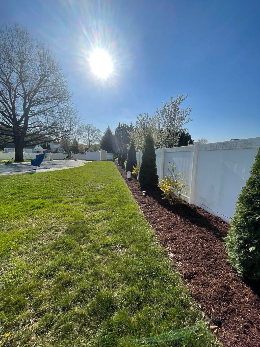Mulched planting bed along a vinyl fence line