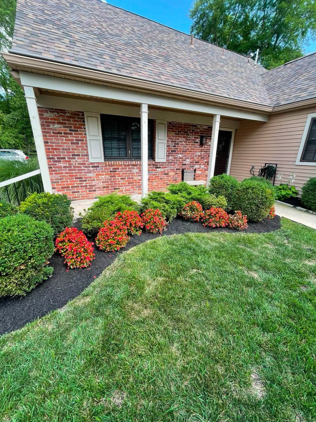 Front planting bed with shrubs and red flowers
