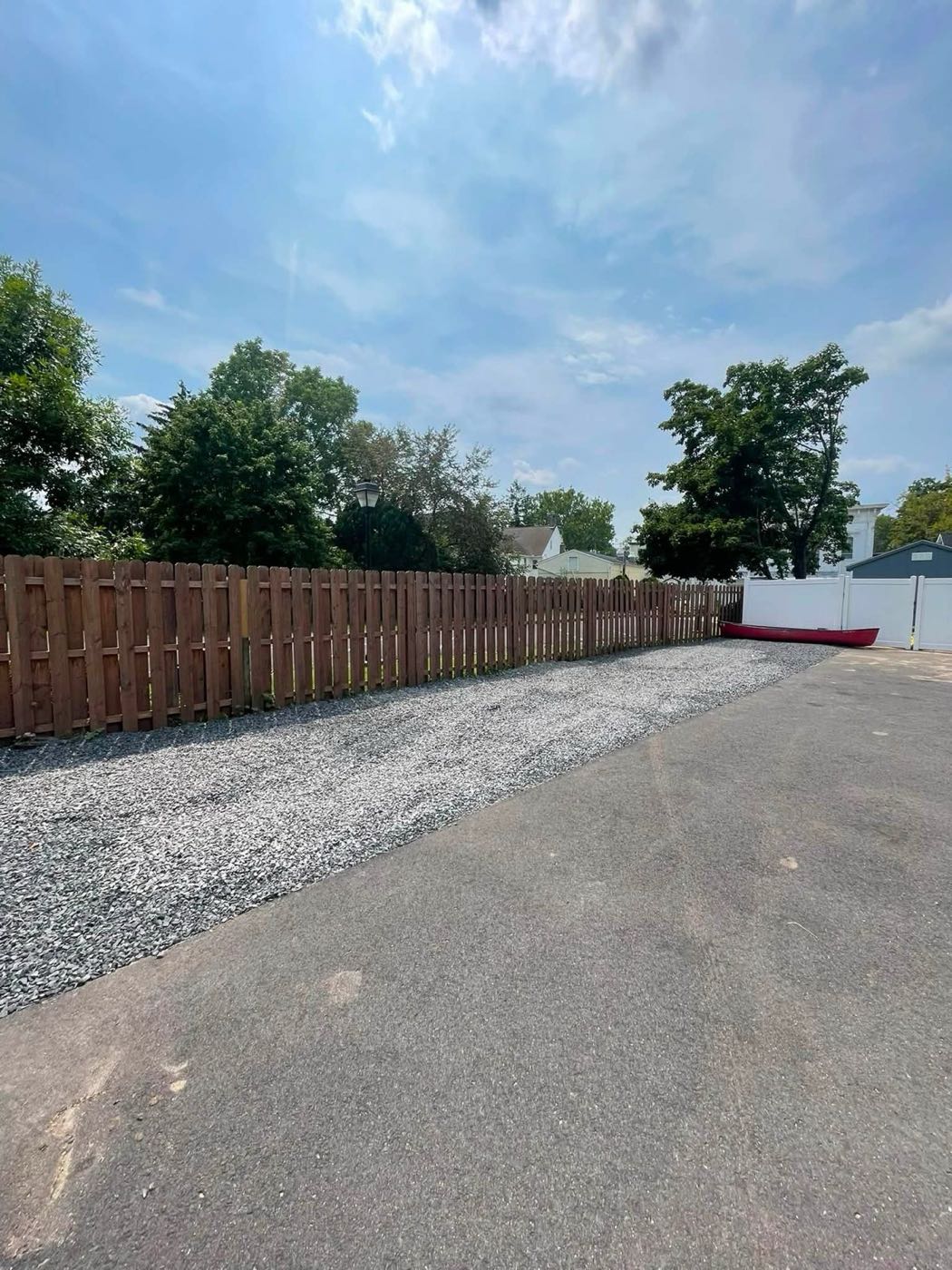 Gravel driveway extension beside a wood fence