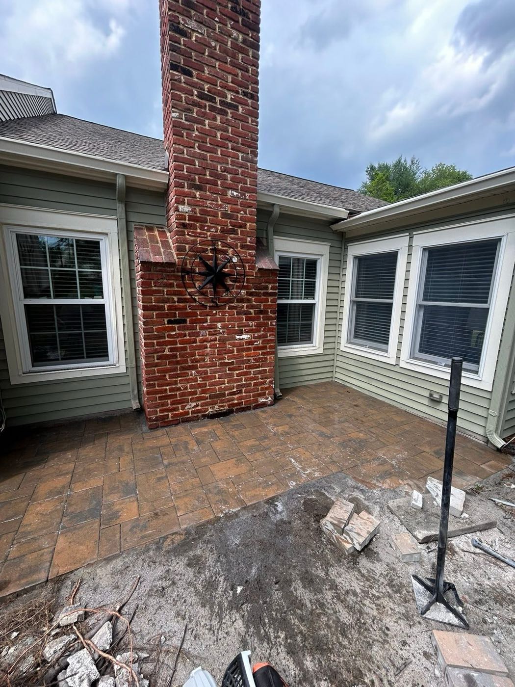 Paver patio extension beside a brick fireplace, during the build