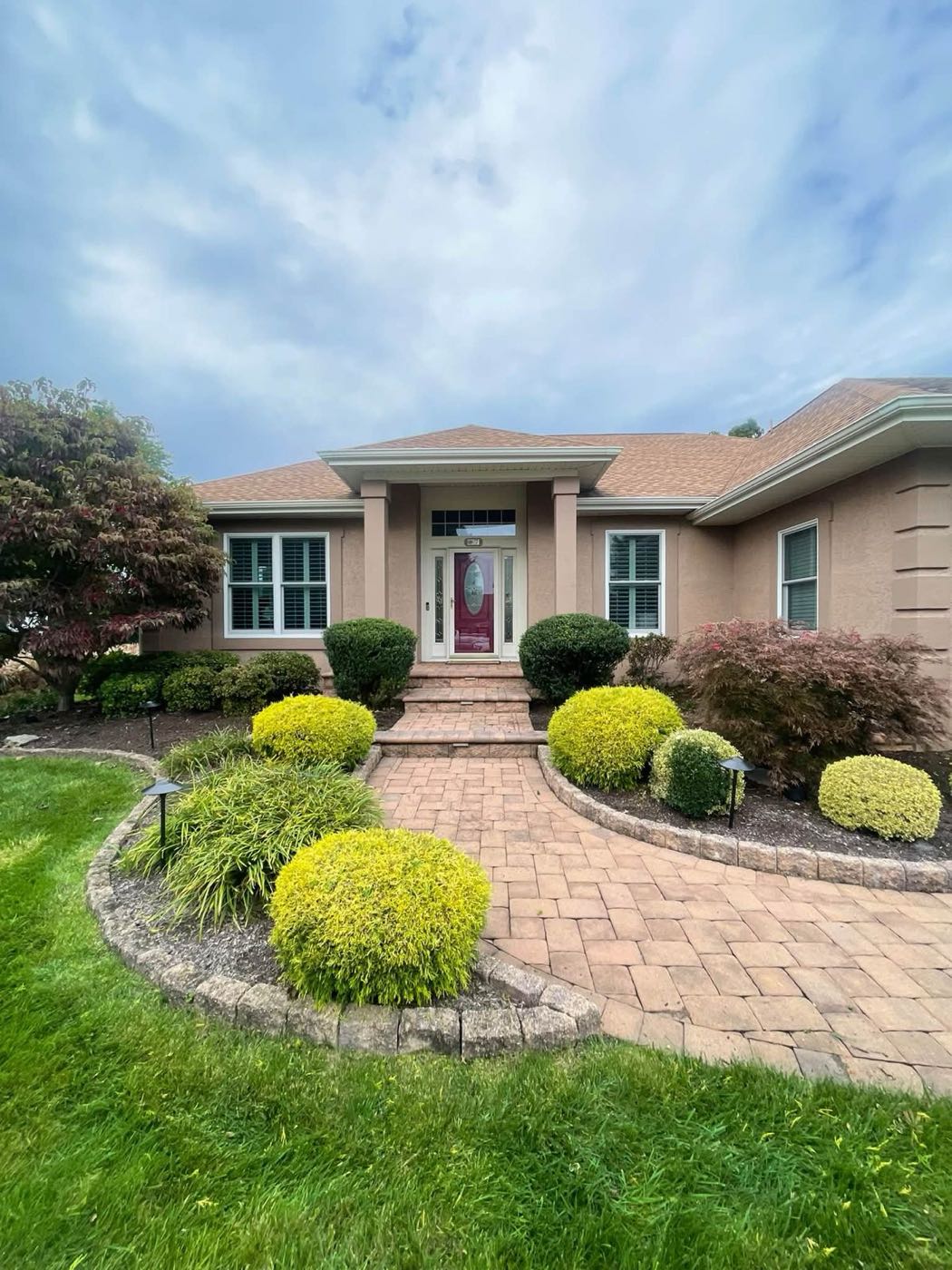 Trimmed shrubs and clean beds along a paver entry walk