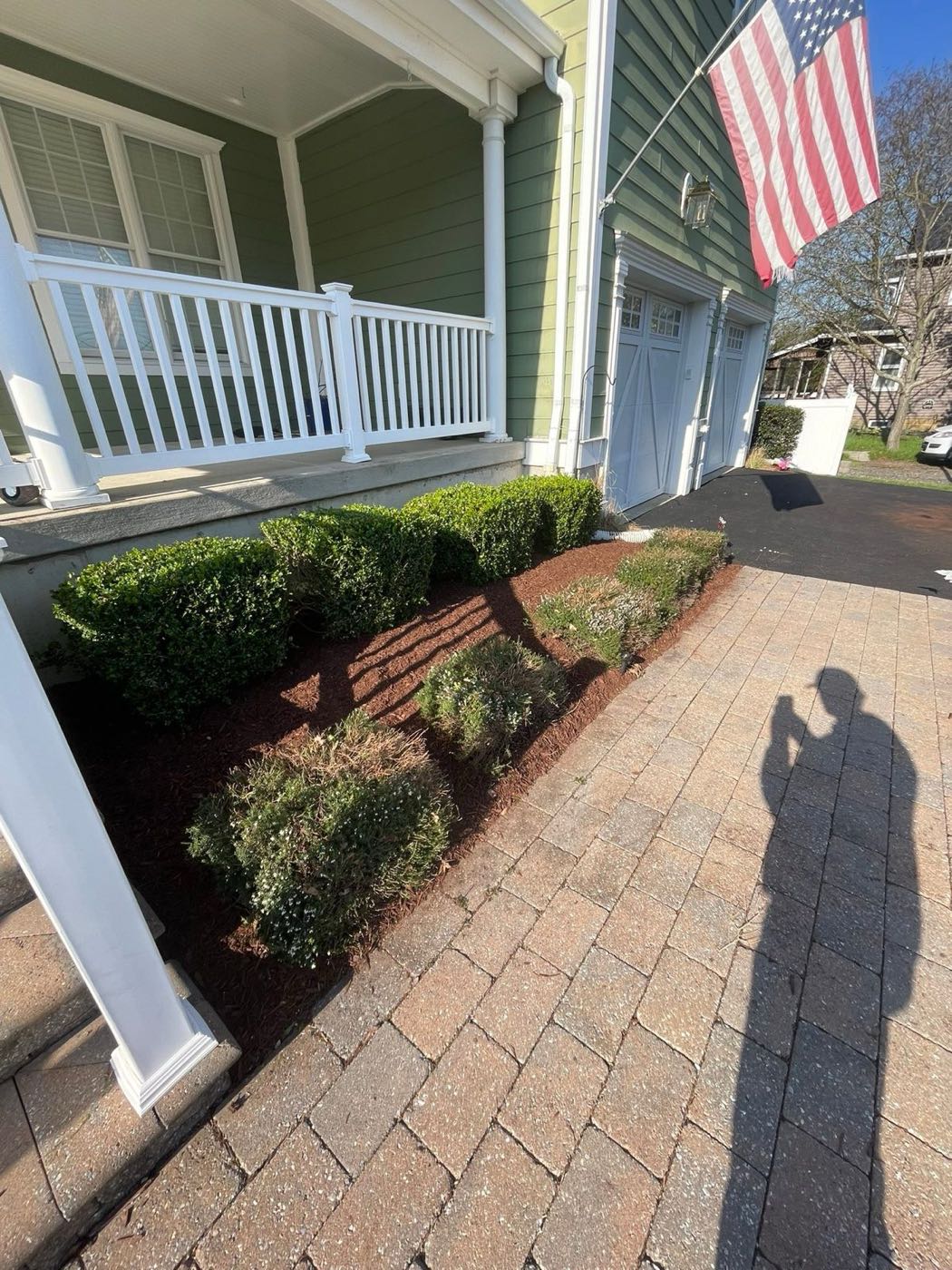 Fresh mulch beds along a front porch and paver walk