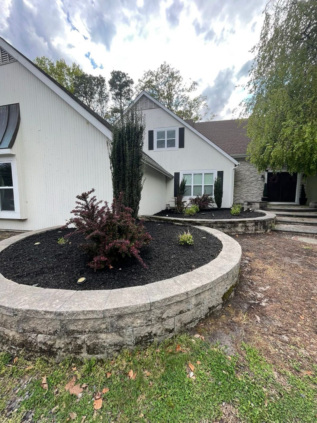 Curved stone raised bed with fresh black mulch