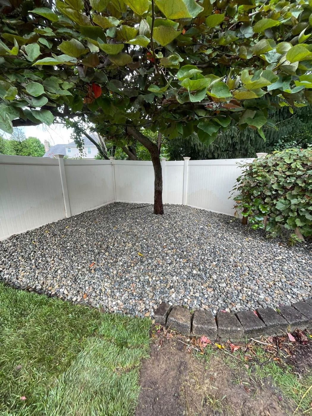 River rock bed around a tree, edged with new sod
